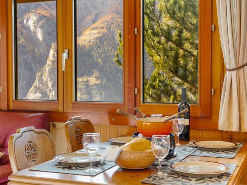 a table with plates and wine glasses in a room with windows at Chalet Als man zählte 1989 by Interhome in Gasenried