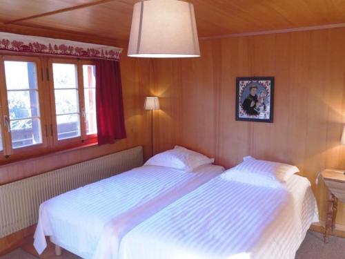a bedroom with two beds and a lamp and two windows at Apartment Tree-Tops- Chalet by Interhome in Gstaad