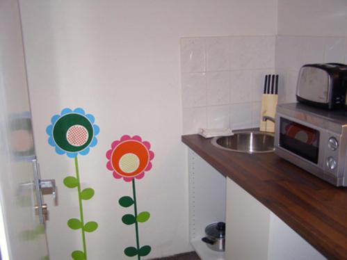 una cocina con flores en la pared junto a un fregadero en Hostel Praha Ládví, en Praga