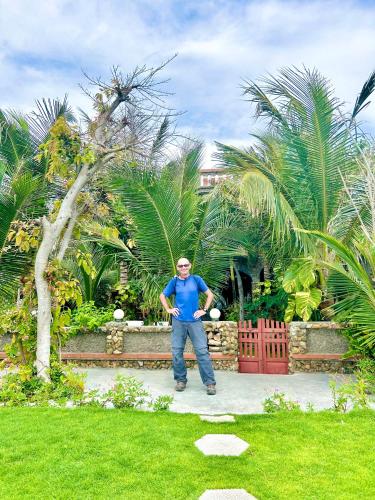 a man standing in front of a garden at Sầm Sơn Boutique Hotel Phan Thiết in Phan Thiet
