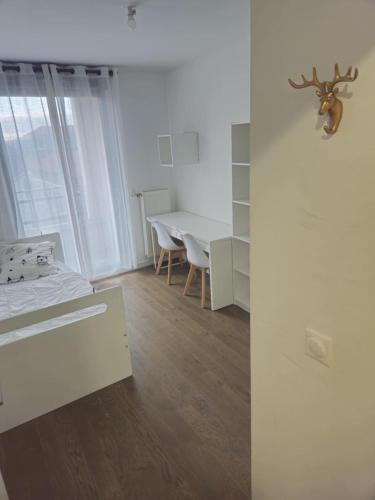 Cette chambre blanche comprend un lit, une table et un bureau. dans l'établissement Le Central, à Colombes