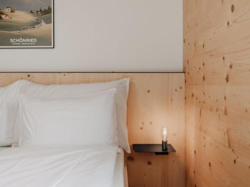 a bed with white pillows and a candle on a side table at Apartment Giferblick by Interhome in Gstaad