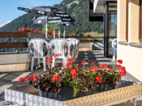 a table with flowers and chairs and an umbrella at Apartment Zurschmitten 11 2- UG Süd by Interhome in Riederalp