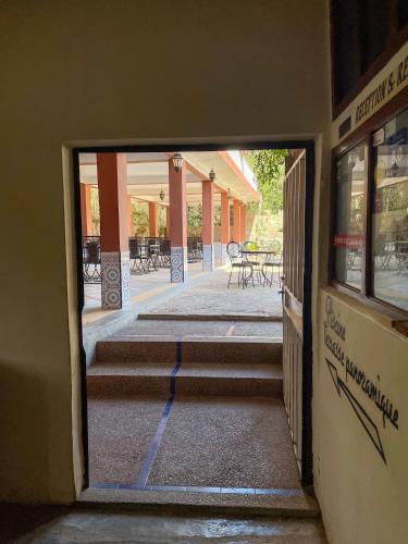 an open door to a building with stairs and tables at tifrit maison d'hôtes-Paradise valley in Imouzzer des Ida Ou Tanane