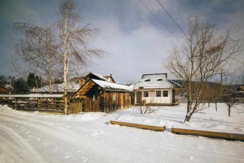 a snowy yard with a barn and a house at Pension La Roata in Gura Humorului