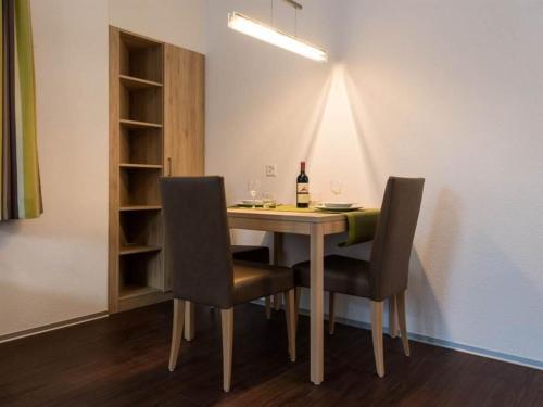 a dining room table with two chairs and a bottle of wine at Apartment Haus Alpenrose by Interhome in Saas-Almagell