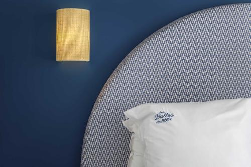 a bed with a white pillow and a blue wall at Les Bulles de Mer - Hotel & Spa sur la Plage in Saint-Cyprien