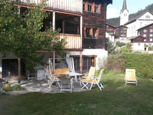 a patio with chairs and a table in front of a house at Apartment ABC Ferienwohnung 3 1- OG Nord-Ost by Interhome in Fiesch