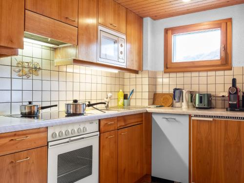uma cozinha com armários de madeira e um fogão branco em Apartment Heimine by Interhome em Grächen