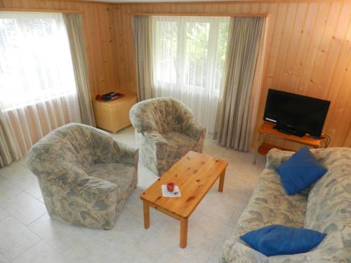 a living room with two chairs and a tv at Apartment Diamant by Interhome in Zweisimmen