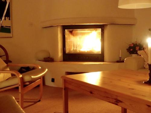 a living room with a fireplace and a wooden table at Apartment Am Schilf by Interhome in Lauenen