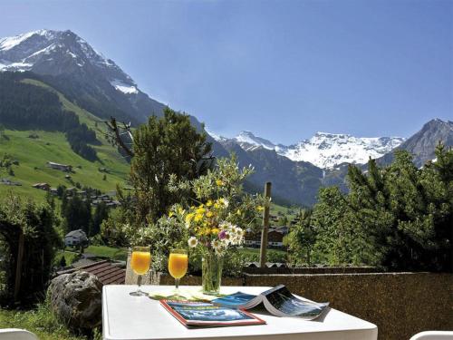 ein Tisch mit zwei Gläsern darauf mit Bergen im Hintergrund in der Unterkunft Apartment Marielle by Interhome in Adelboden