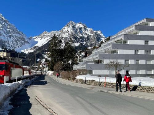 two people standing on the side of a street with a mountain at Apartment Sunnmatt West Wohnung 936 by Interhome in Engelberg