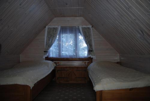 a attic room with two beds and a window at Prie Klykio in Utena