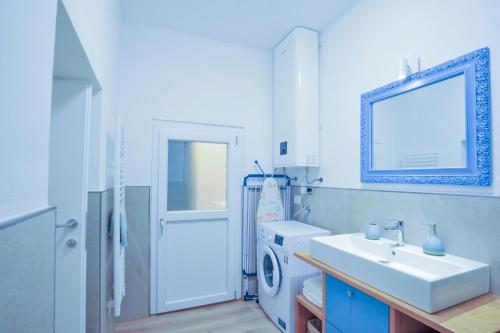 La salle de bains blanche est pourvue d'un lavabo et d'un lave-linge. dans l'établissement Casa Pepi City Center, à Sanremo
