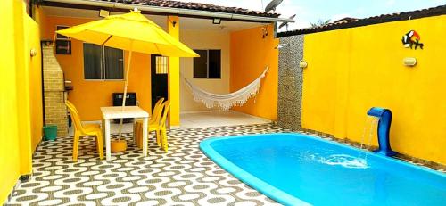 una casa gialla con piscina, tavolo e ombrellone di Casa São Miguel dos Milagres a São Miguel dos Milagres