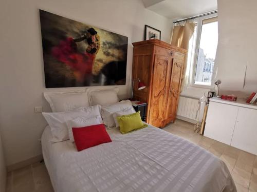 - une chambre avec un lit blanc et 2 oreillers colorés dans l'établissement Joli Cocon avec Terrasse dans Le Marais, à Paris