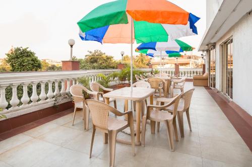 a row of tables and chairs with umbrellas on a balcony at Garden Hotel in Mumbai