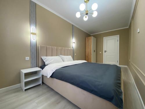 a bedroom with a large bed and a chandelier at Люксовая квартира in Taraz