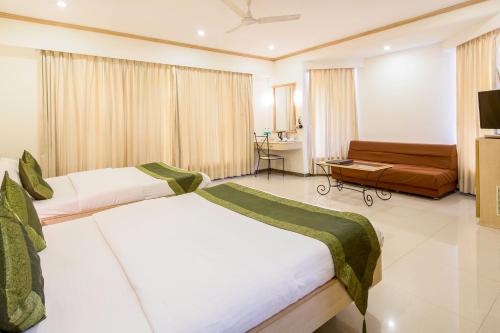 a hotel room with two beds and a couch at Garden Hotel in Mumbai