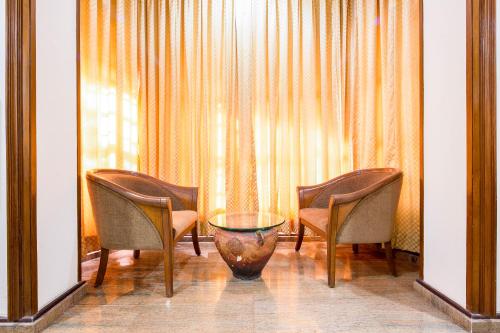 a room with three chairs and a vase in front of a window at Garden Hotel in Mumbai
