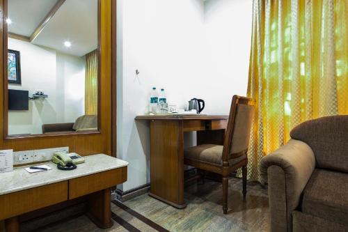 a room with a desk and a chair and a mirror at Garden Hotel in Mumbai