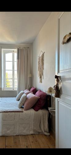 ein Schlafzimmer mit einem Bett mit Kissen und einem Fenster in der Unterkunft Le logis blanc bed&breakfast in Coursan