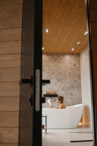 a woman sitting in a bath tub in a bathroom at Vdoma Karpaty in Vilshynki