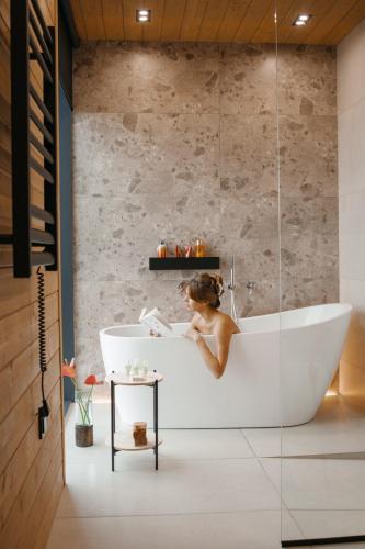 a woman sitting in a bath tub in a bathroom at Vdoma Karpaty in Vilshynki