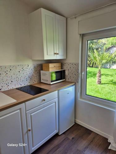 une cuisine avec des placards blancs et une fenêtre avec une cour dans l'établissement Studio de plain-pied, à Beauchamp