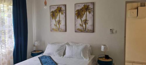 a bedroom with a bed with two pictures on the wall at Kaz KAFE in Mamoudzou