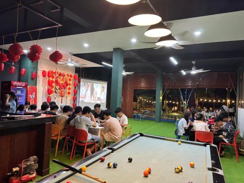 a group of people sitting around a pool table in a restaurant at King Bavi Resort in Ba Vì