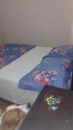 a dog is standing next to a bed with a table at Hospedaria meu Lar in Rio das Ostras