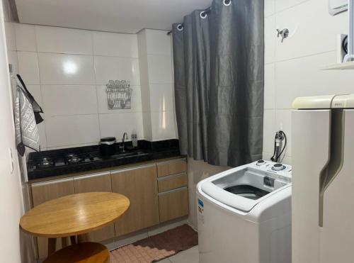 een kleine keuken met een wasmachine en een tafel bij Apartamento Setor Universitário in Goiânia