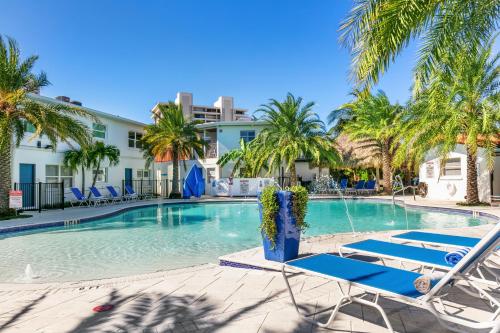 a swimming pool with lounge chairs and palm trees at Siesta Key Beach Resort and Suites in Sarasota