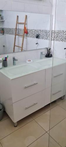 a white bathroom with a sink and a mirror at Kaz KAFE in Mamoudzou