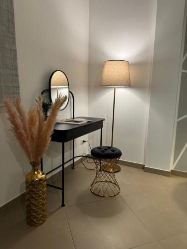 a desk with a mirror and a stool and a lamp at Samarè Rooms & Apartments in Bisceglie