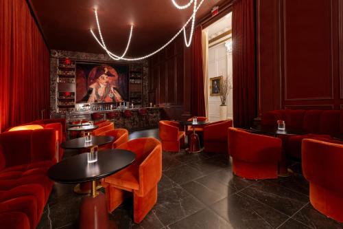 a restaurant with red chairs and tables and a painting at Le Pavillon, New Orleans, a Tribute Portfolio Hotel in New Orleans
