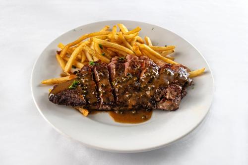 a plate of steak and french fries on a table at Le Pavillon, New Orleans, a Tribute Portfolio Hotel in New Orleans