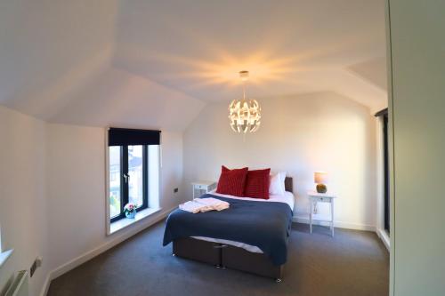 a bedroom with a bed with red pillows and a chandelier at Maidenhead Stylish Three Bedroom Top Floor Apartment in Maidenhead