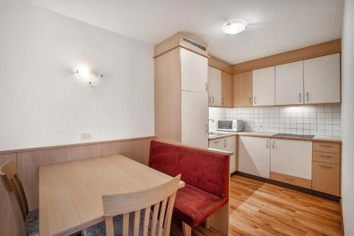 a small kitchen with a table and a red chair at Residence Linderhof in Naz-Sciaves