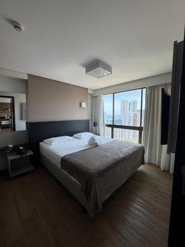 a bedroom with a large bed and a large window at Pontes Home Stay - Flats em Boa Viagem por Yolo in Recife