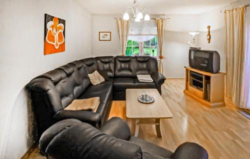 a living room with a black leather couch and a table at Ferienwohnung Zirtow in Mirow