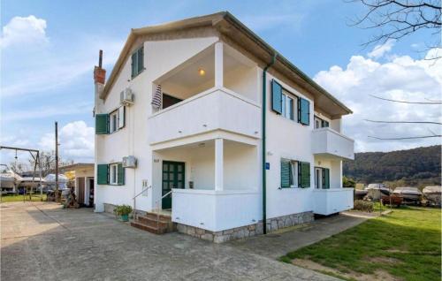 a white house with green shutters at Apartment Nedo in Supetarska Draga