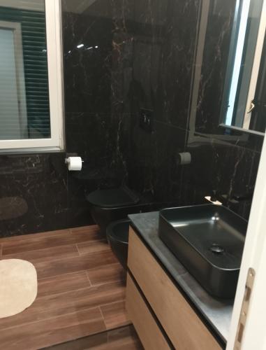a black bathroom with a sink and two toilets at Stella Polare Sensorial Home in Lido di Ostia