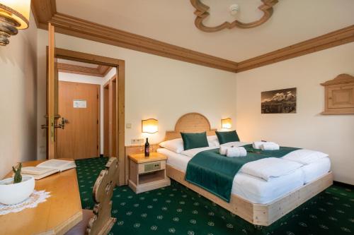 a bedroom with a large bed and a table and a desk at Landhaus St. Georg in Gröbming
