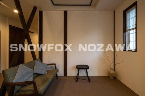 a living room with a couch and a stool at Snowfox Nozawa in Nozawa Onsen