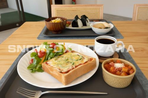 a tray with a plate of food with a sandwich and salad at Snowfox Nozawa in Nozawa Onsen