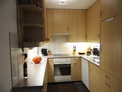 a kitchen with wooden cabinets and white appliances at Apartment Sunnmatt Süd Wohnung 432 by Interhome in Engelberg