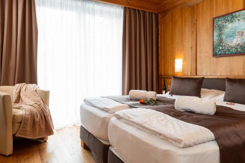 a hotel room with two beds and a chair at Landhaus St. Georg in Gröbming